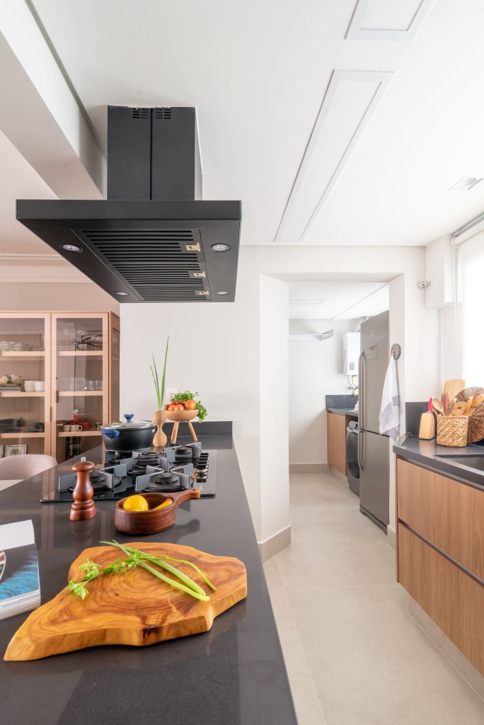 Reforma de cozinha antes e depois: 4 projetos funcionais e surpreendentes. Projeto de Isabella Nalon. Na foto, cozinha com bancada preta, coifa preta.