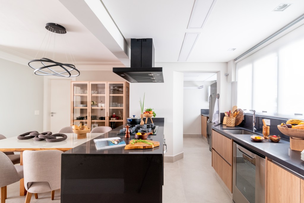 Reforma de cozinha antes e depois: 4 projetos funcionais e surpreendentes. Projeto de Isabella Nalon. Na foto, cozinha integrada com bancada preta.