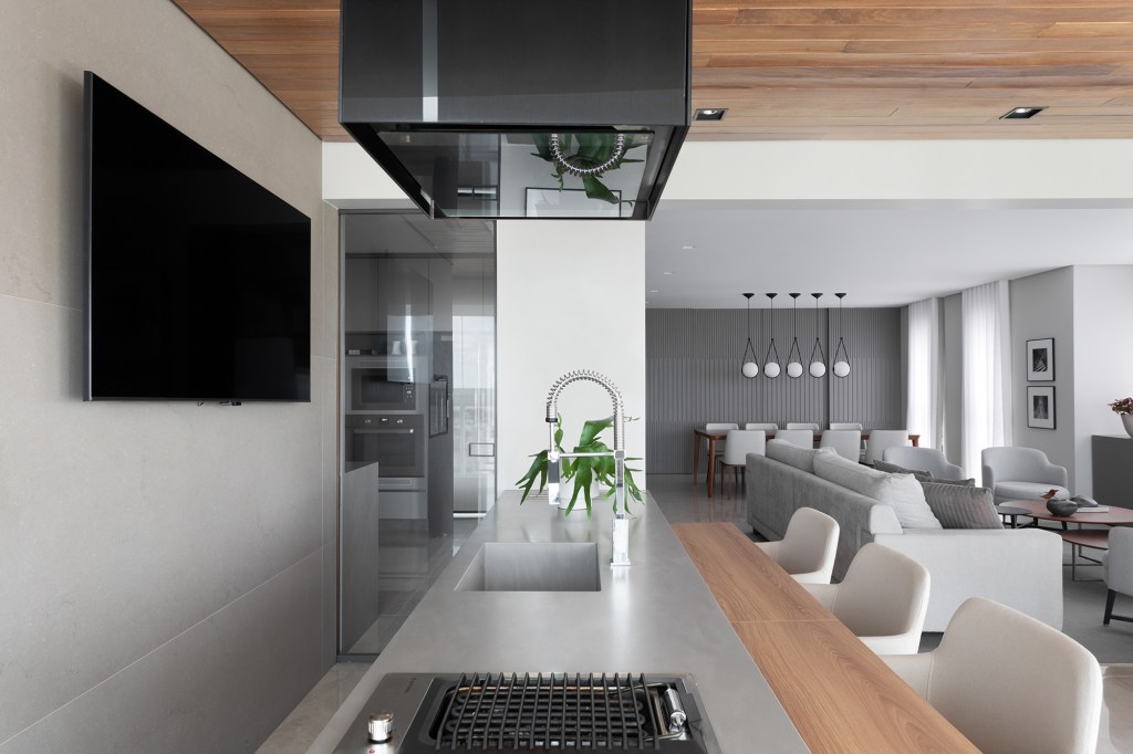 Tons de cinza criam elegância neste apartamento de 256 m². Projeto de arch.lab. Na foto, cozinha com marcenaria cinza e torre quente. Sala de jantar com ilha.