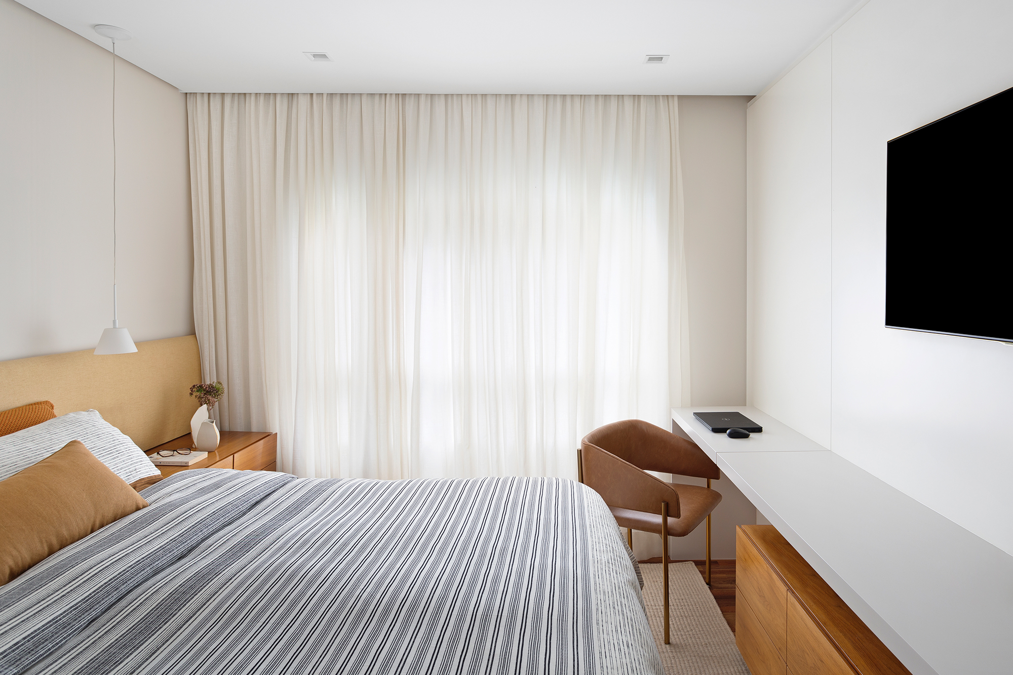 Apartamento de 151 m² ganha bar de mármore logo na entrada. Projeto de Ana Toscano Arquitetura. Na foto, quarto de casal com TV e espaço para home office.