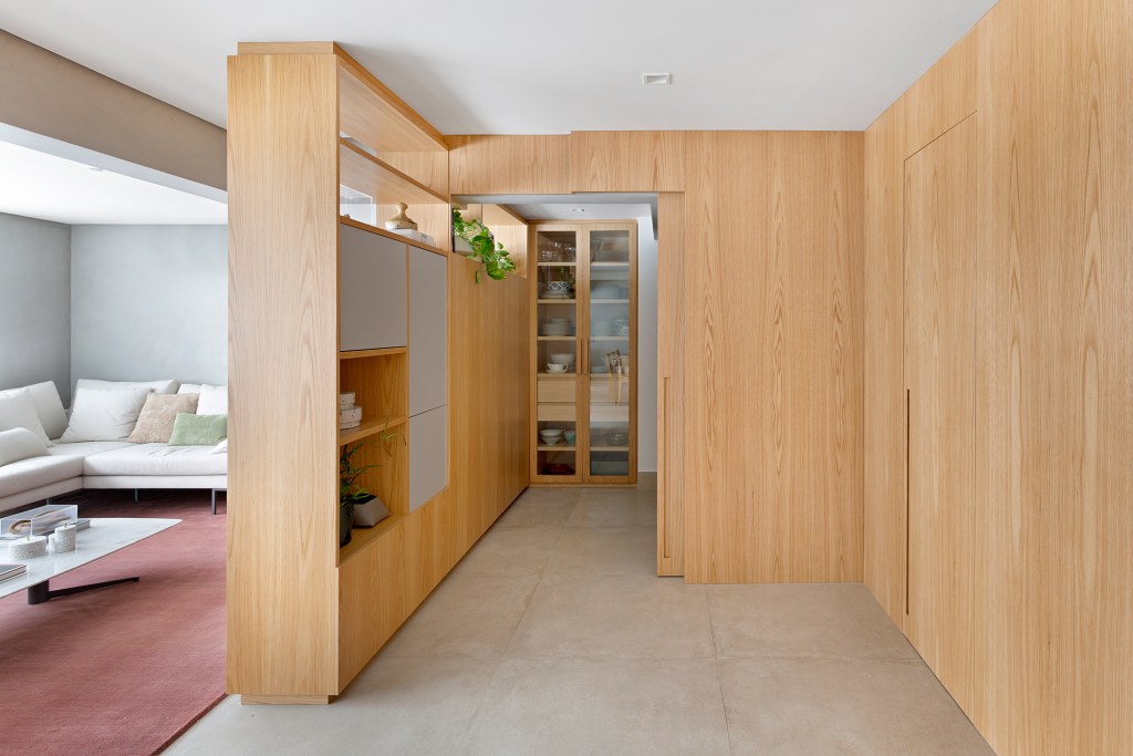 Apartamento de 151 m² ganha bar de mármore logo na entrada. Projeto de Ana Toscano Arquitetura. Na foto, painel estante de madeira. Cristaleira na cozinha.