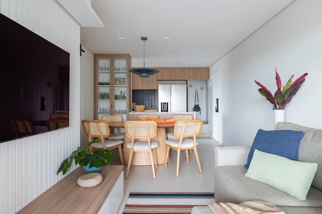 Apartamento de 83 m² ganha décor acolhedor sem derrubar nenhuma parede. Projeto do Estúdio Maré, Na foto, sala de estar a jantar com tv e mesa redonda.