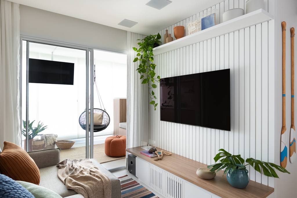 Apartamento de 83 m² ganha décor acolhedor sem derrubar nenhuma parede. Projeto do Estúdio Maré, Na foto, sala de estar com parede ripada e varanda com balanço.