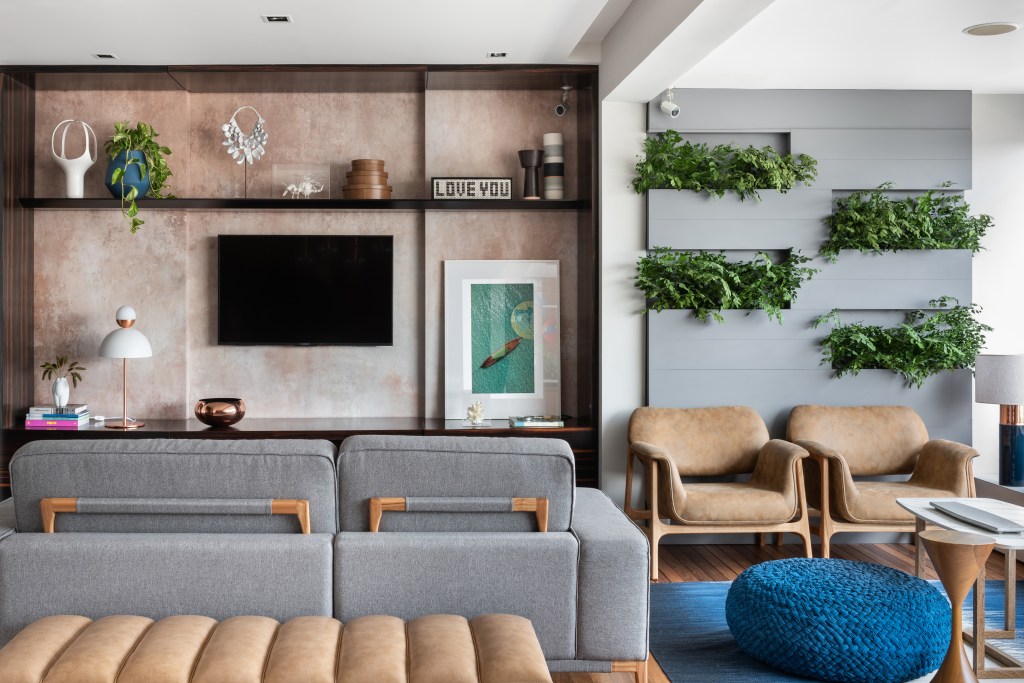 Apartamento ganha décor com tons de azul, cinza e madeira. Projeto de Beatriz Quinelato. Na foto, sala de TV com papel de parede e varanda com jardim vertical.