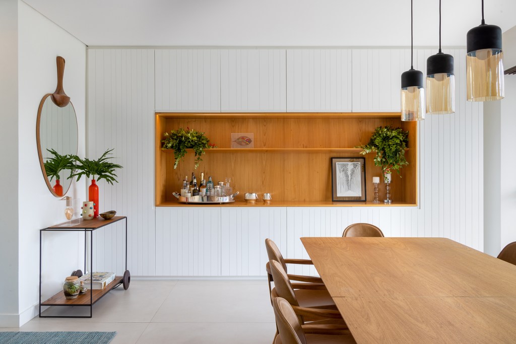 Apartamento solar de 300 m² é feito para receber amigos. Projeto de Ana Veira. Na foto, sala de jantar com bar e armários.