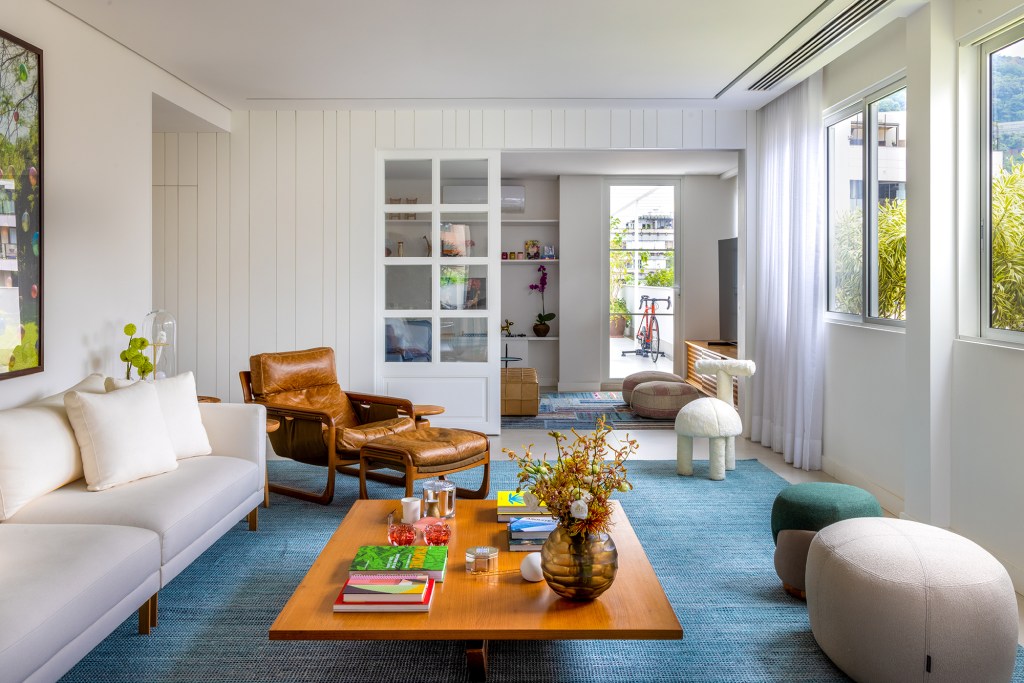 Apartamento solar de 300 m² é feito para receber amigos. Projeto de Ana Veira. Na foto, sala de estar com tapete azul, porta de correr que separa da sala de TV.