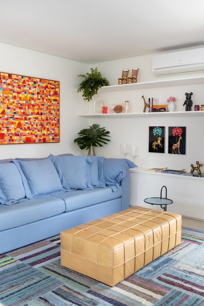Apartamento solar de 300 m² é feito para receber amigos. Projeto de Ana Veira. Na foto, sala de estar com sofá azul e quadro vermelho.