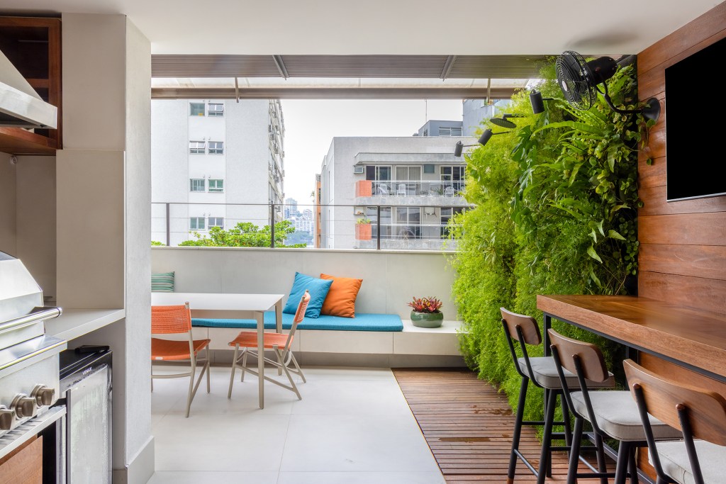 Apartamento solar de 300 m² é feito para receber amigos. Projeto de Ana Veira. Na foto, sala de jantar e varanda com sofá.