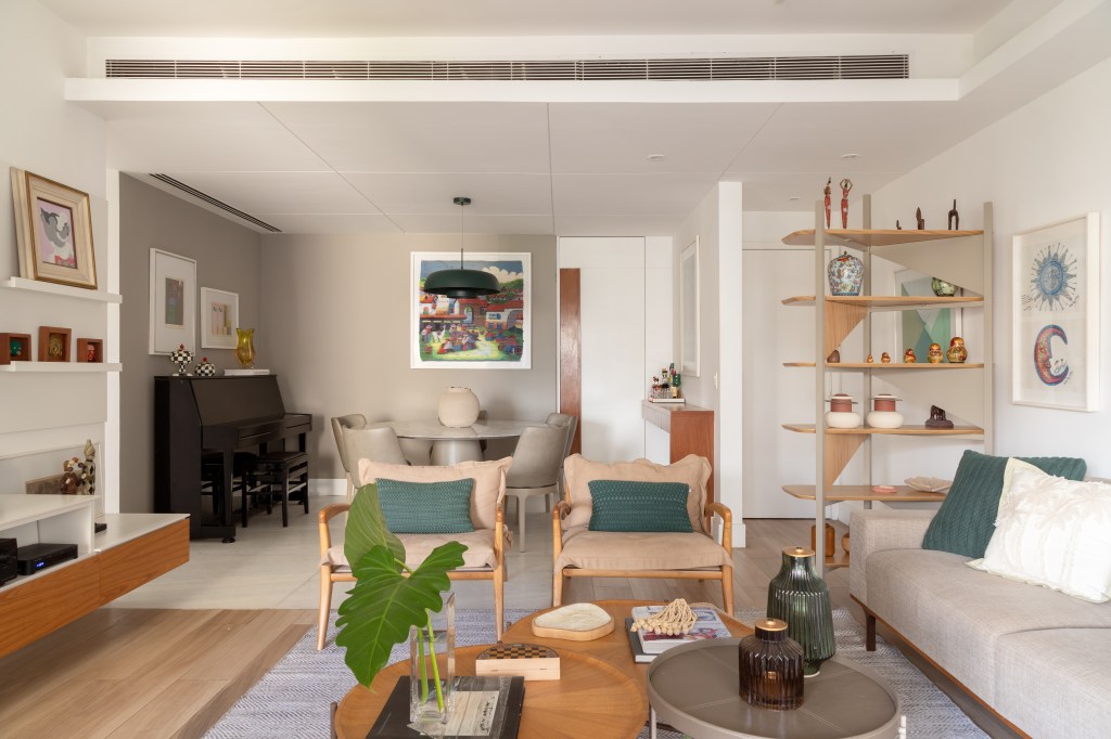 Apê de 150 m² ganha cozinha em tom verde suave e estante vazada na sala. Projeto de Ana Cano. Na foto, sala de estar, poltronas, mesas de centro redondas.