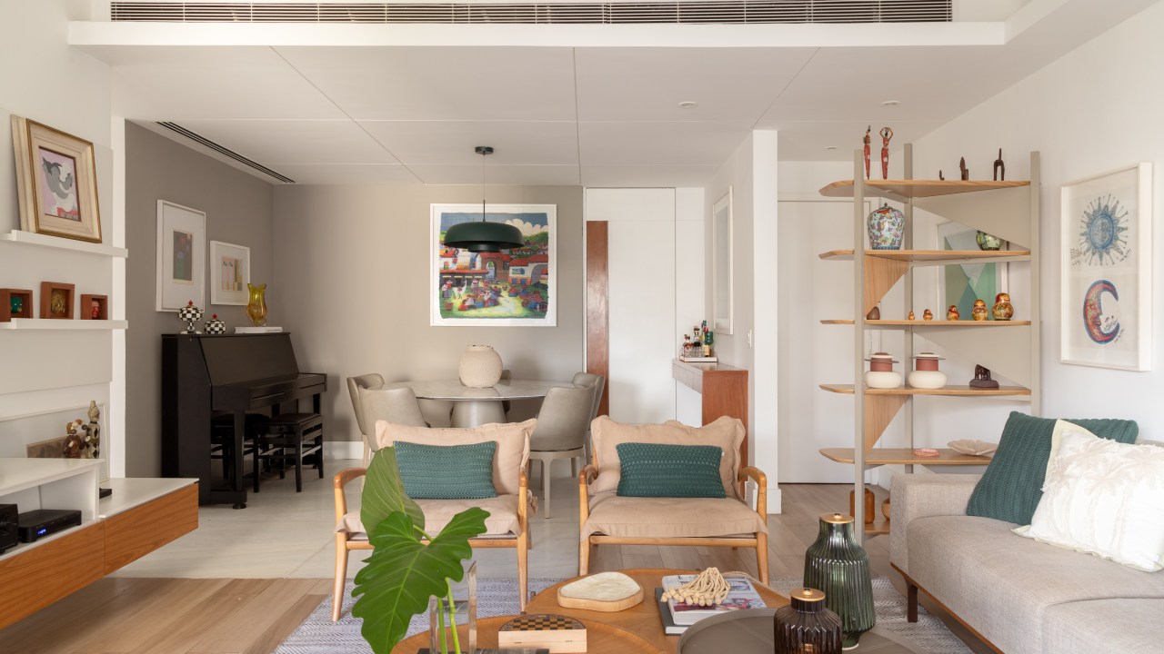 Apê de 150 m² ganha cozinha em tom verde suave e estante vazada na sala. Projeto de Ana Cano. Na foto, sala de estar, poltronas, mesas de centro redondas.