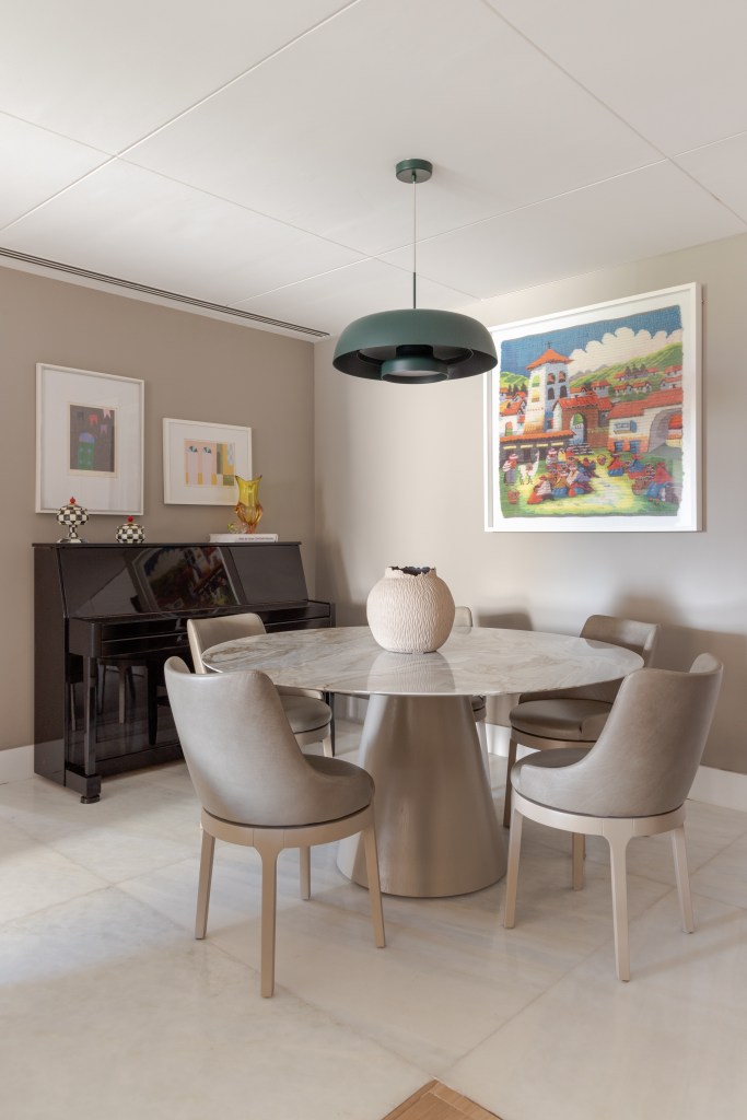 Apê de 150 m² ganha cozinha em tom verde suave e estante vazada na sala. Projeto de Ana Cano. Na foto, sala de jantar, mesa redonda, cadeiras cinzas, piano.