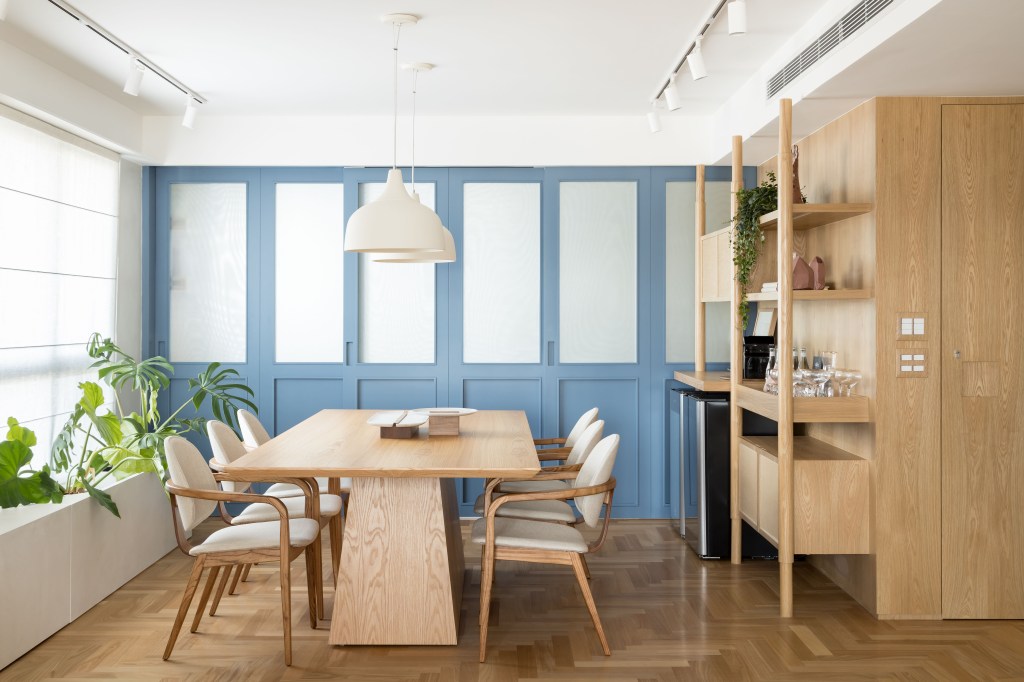 Apê de 180 m² ganha azul na marcenaria e nos revestimentos da cozinha. Projeto de Studio LAK. Na foto, sala de jantar, mesa de madeira, luminária branca, cadeiras brancas, porta de correr.