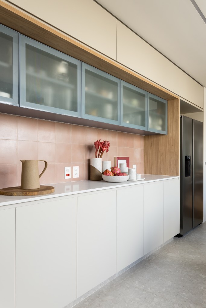Apê de 180 m² ganha azul na marcenaria e nos revestimentos da cozinha. Projeto de Studio LAK. Na foto, bancada branca, armário com porta de vidro canelado.