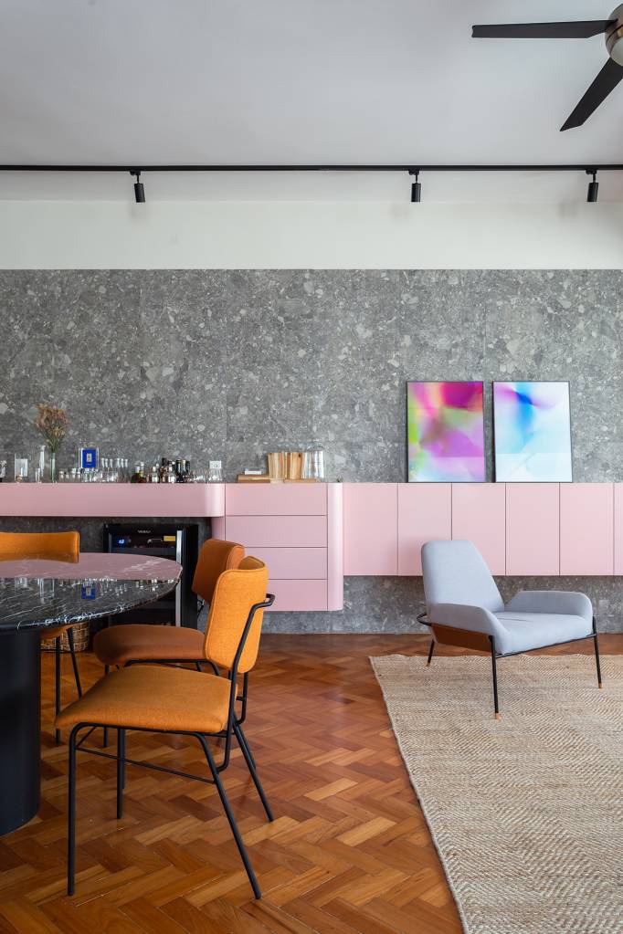 Apê de 192 m² mescla estilos industrial e brutalista com pitadas de cor. Projeto de Zimbro Arquitetura. Na foto, sala de jantar com parede de concreto e aparador rosa.