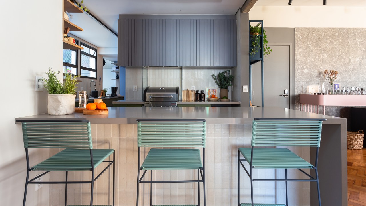 Apê de 192 m² mescla estilos industrial e brutalista com pitadas de cor. Projeto de Zimbro Arquitetura. Na foto, cozinha com balcão e marcenaria ripada.