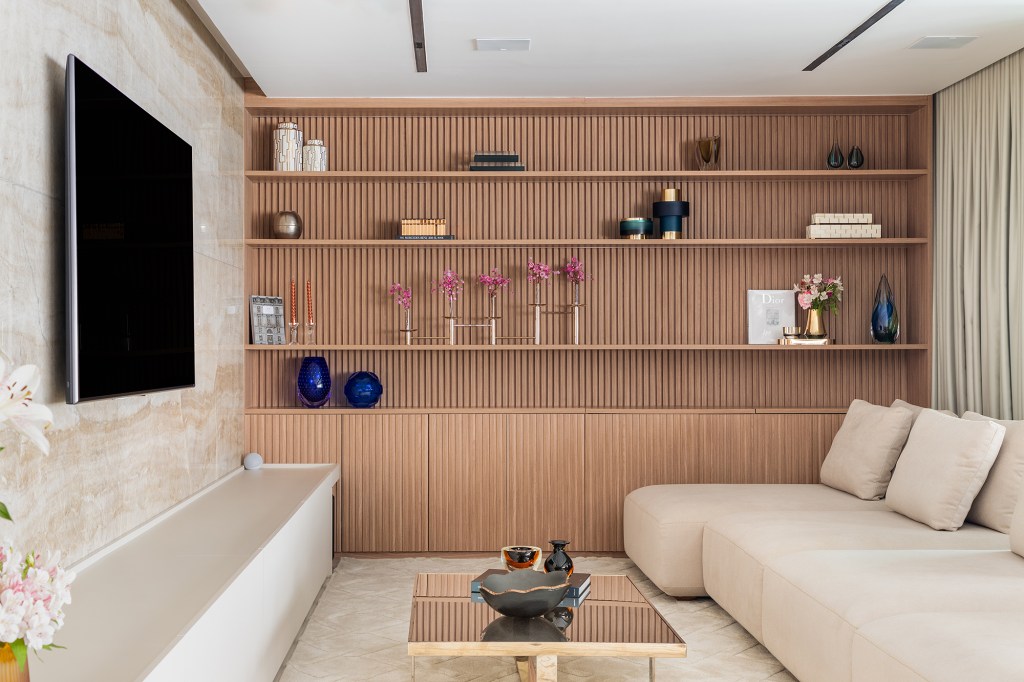 Apê de 275 m² ganha canto do café com vista para a cidade de São Paulo. Projeto de Thiemi Hernandes. Na foto, sala de TV com estante ripada e painel de mármore.
