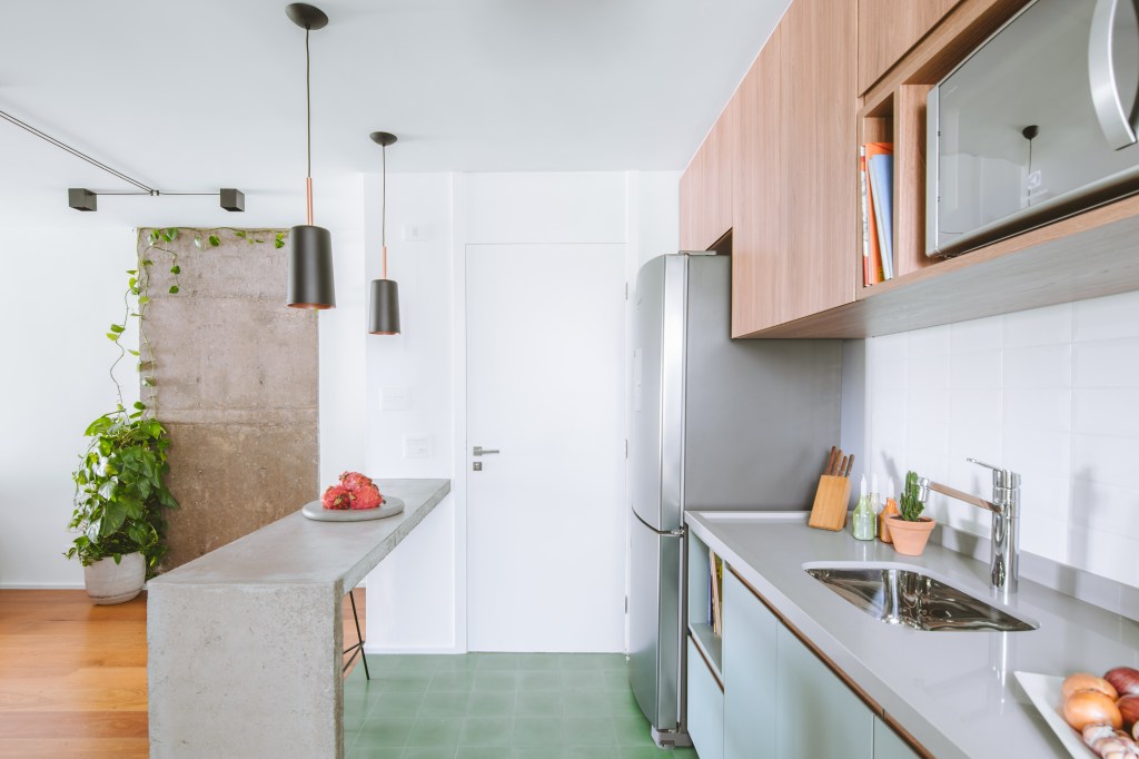 Apê industrial de 75 m² tem cozinha verde menta com bancada de cimento. Projeto de Rawi Arquitetura + Design. Na foto, bancada de cozinha, backsplash de subway tiles.