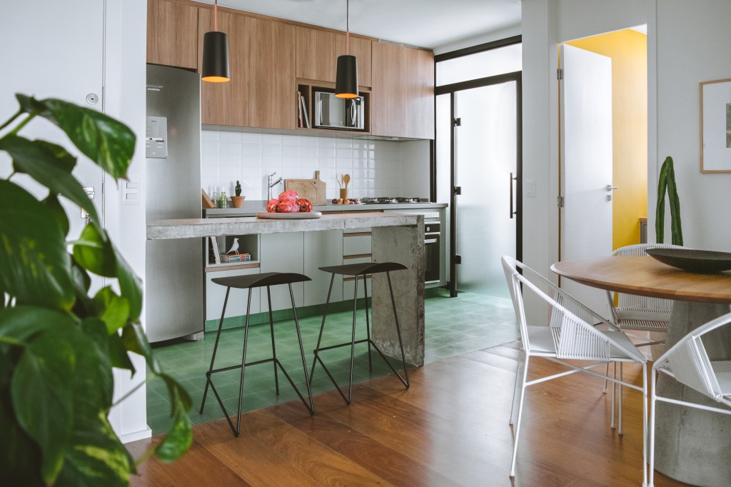 Apê industrial de 75 m² tem cozinha verde menta com bancada de cimento. Projeto de Rawi Arquitetura + Design. Na foto, piso de ladrilho, banqueta preta.
