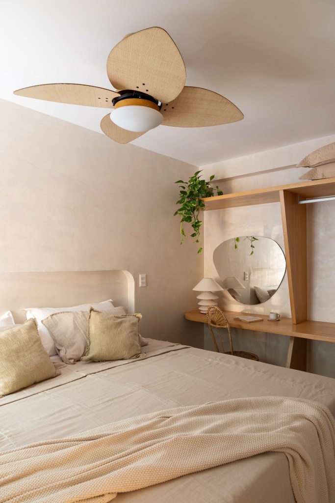 Apê térreo de 45 m² ganha cara de casa de praia com área externa integrada. Projeto de Casa Tauari. Na foto, quarto com penteadeira, espelho em formato orgânico, abajur branco, ventilador de teto.