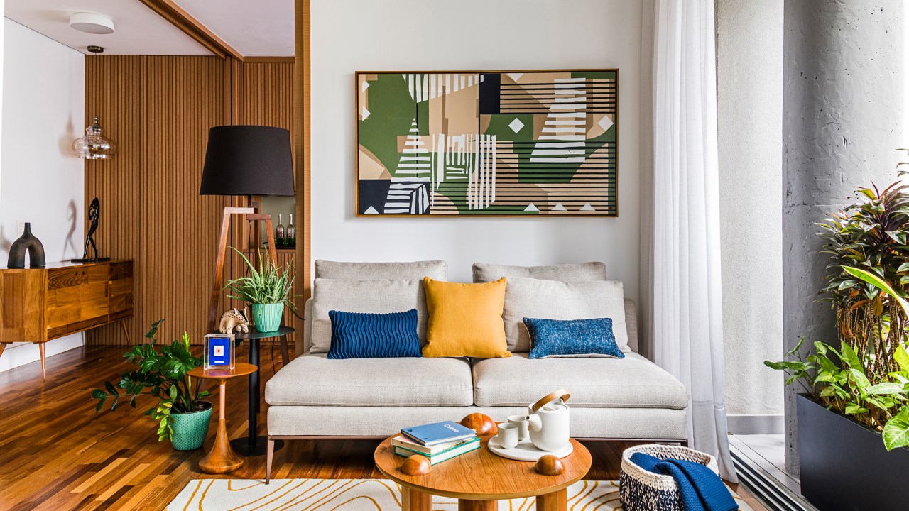Azulejos estampados e cores trazem personalidade a apê de 100 m². Projeto de Carolina Munhoz. Na foto, sala de estar com sofá. quadro e parede ripada.