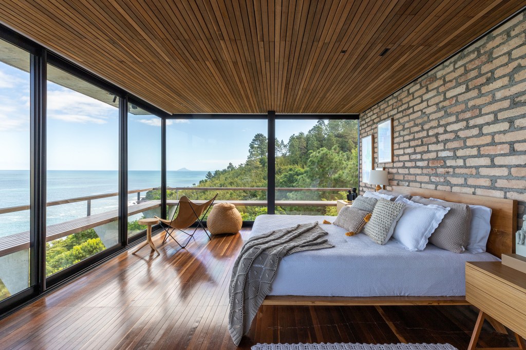 Casa de praia de 150 m² parece flutuar em meio à natureza. Projeto de Studio Carlito e Renata Pascucci. Na foto, quarto com vista para o mar e parede de tijolos.