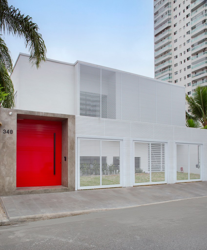 Casa ganha segundo andar e decoração inspirada no automobilismo. Projeto de Gabriel Fernandes. Na foto, fachada, porta vermelha.