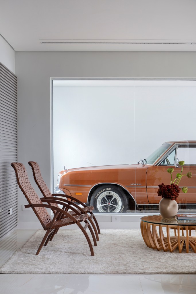 Casa ganha segundo andar e decoração inspirada no automobilismo. Projeto de Gabriel Fernandes. Na foto, sala de estar, lamina de vidro para garagem, carro.