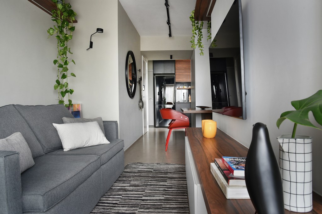 Com apenas 56 m², apartamento ganha décor jovem e descolado. Projeto de Flavia Campos e Sandra Paes. Na foto, sala de estar com TV, jantar integrado e sofá cinza.