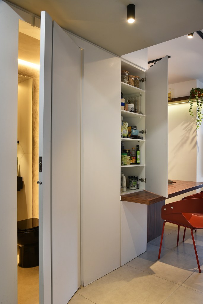 Com apenas 56 m², apartamento ganha décor jovem e descolado. Projeto de Flavia Campos e Sandra Paes. Na foto, painel de marcenaria que camufla lavabo e despensa.
