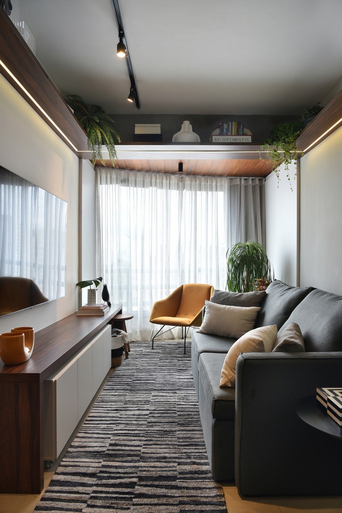 Com apenas 56 m², apartamento ganha décor jovem e descolado. Projeto de Flavia Campos e Sandra Paes. Na foto, sala de estar com TV, tapete e poltrona.