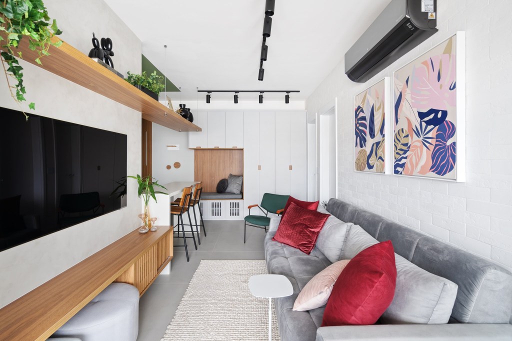 Com circulação otimizada, apê de 49 m² tem tons de verde e madeira. Projeto de Natalia Salla. Na foto, sofá cinza, sala de estar, trilho de spots, prateleira.