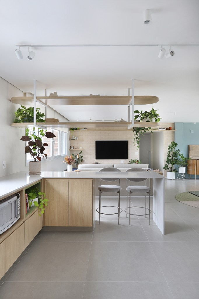 Cozinha verde e espaço para a cachorrinha marcam apê de casal gamer. Projeto de Studio 92 Arquitetura. Na foto. sala integrada com cozinha e balcão de refeições.