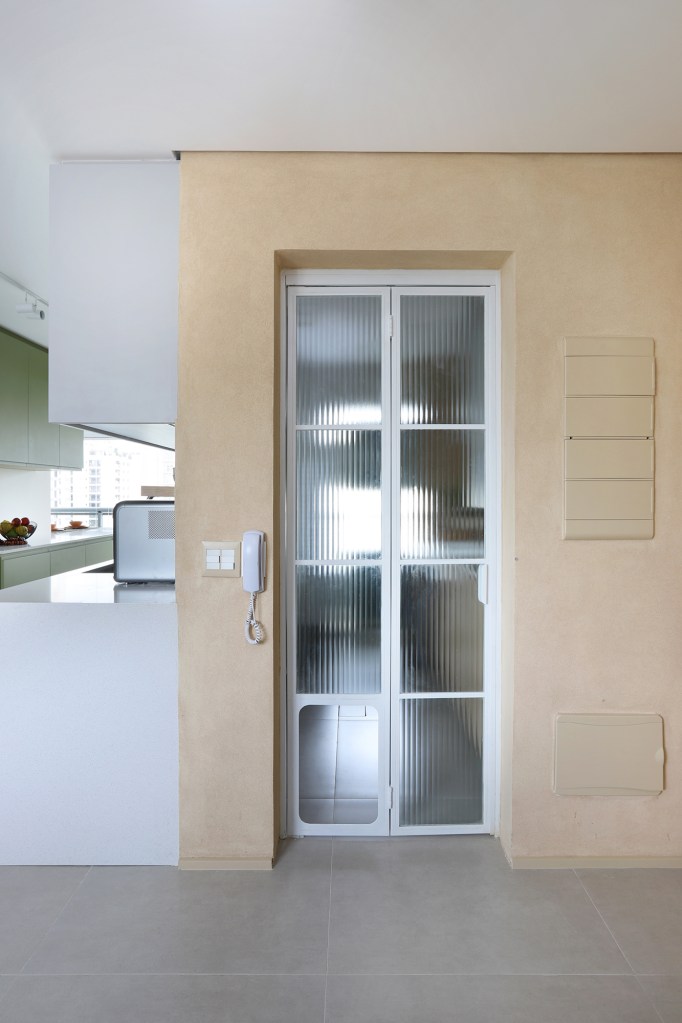 Cozinha verde e espaço para a cachorrinha marcam apê de casal gamer. Projeto de Studio 92 Arquitetura. Na foto. porta da lavanderia com espaço para o cachorro.