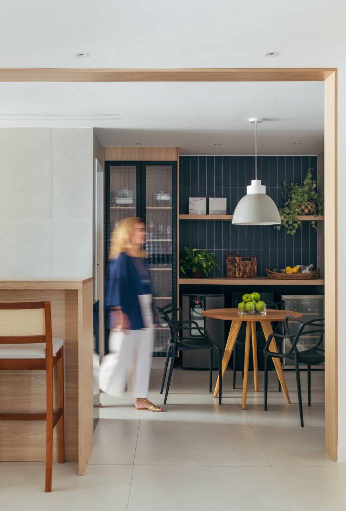 Dois apês viram um com cozinha gourmet, jantar e sala de TV integradas. Projeto de Fernanda Medeiros. Na foto, cozinha, parede de azulejos azuis, copa para refeições, mesa redonda pequena.