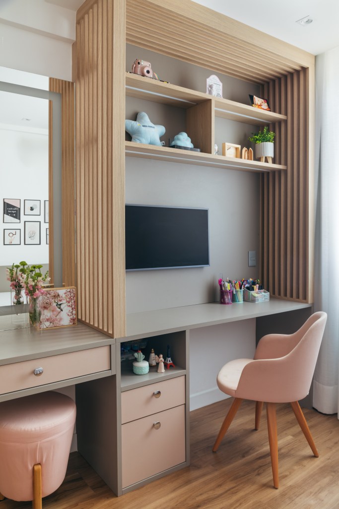 Dois apês viram um com cozinha gourmet, jantar e sala de TV integradas. Projeto de Fernanda Medeiros. Na foto, quarto com penteadeira, tv, cadeira rosa.