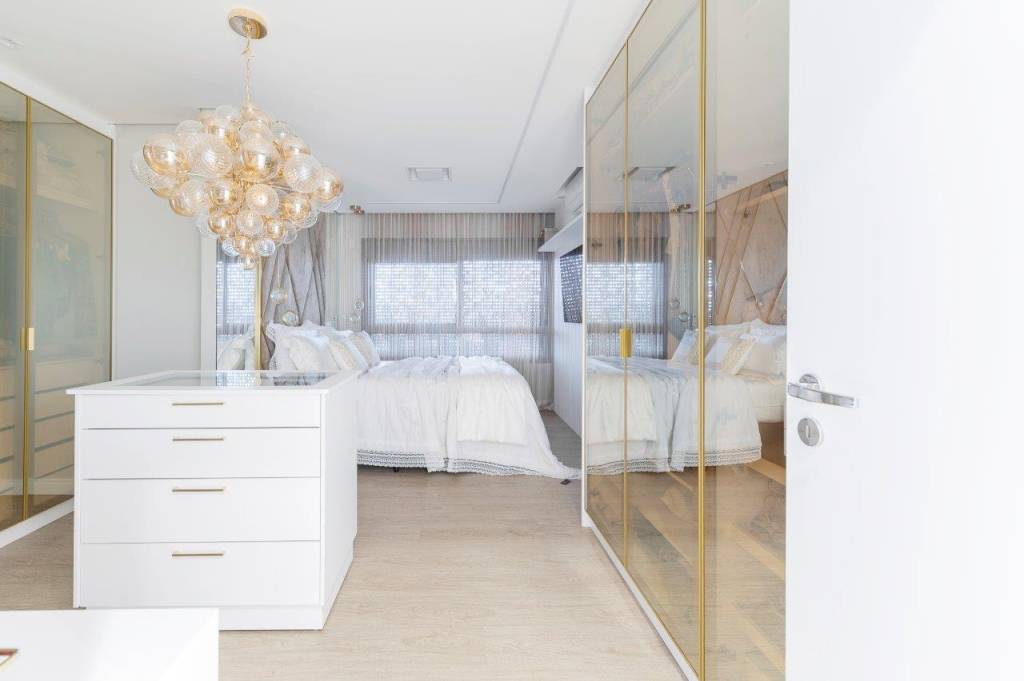 dourado-pendentes-serralheria-metais-brilho-ape-marcela-rocca-14-quarto-closet Dourado nos pendentes, serralheria e metais dão brilho à apê. Projeto de Marcela Rocca. Na foto, quarto com closet, lustre, armários espelhados e ilha.