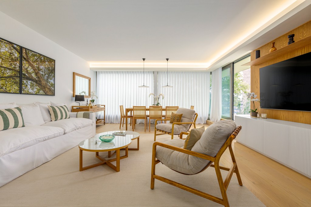 Feito à distância, apê de 160 m² em Portugal ganha décor com clima carioca. Projeto de C.W. Arquitetura. Na foto, sala de estar e jantar com quadros na parede, sofá e mesas.
