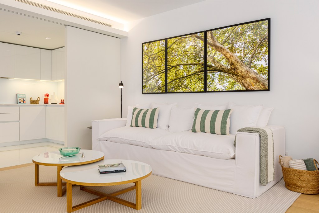 Feito à distância, apê de 160 m² em Portugal ganha décor com clima carioca. Projeto de C.W. Arquitetura. Na foto, sala com quadros e sofá branco.
