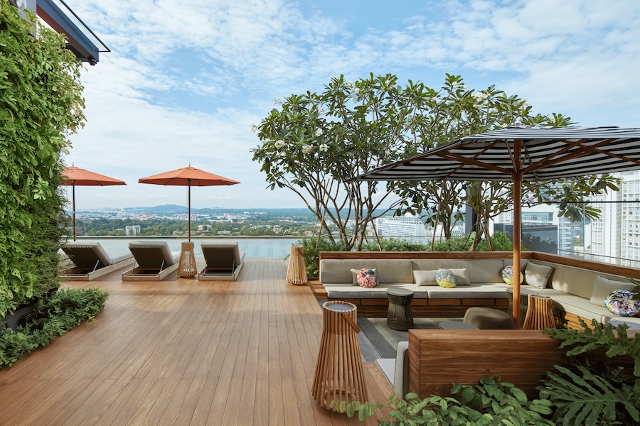 Hotel em Singapura destaca-se pelos grandes jardins verticais tropicais. Na foto, terraço com deck de madeira, piscina, espreguiçadeiras.