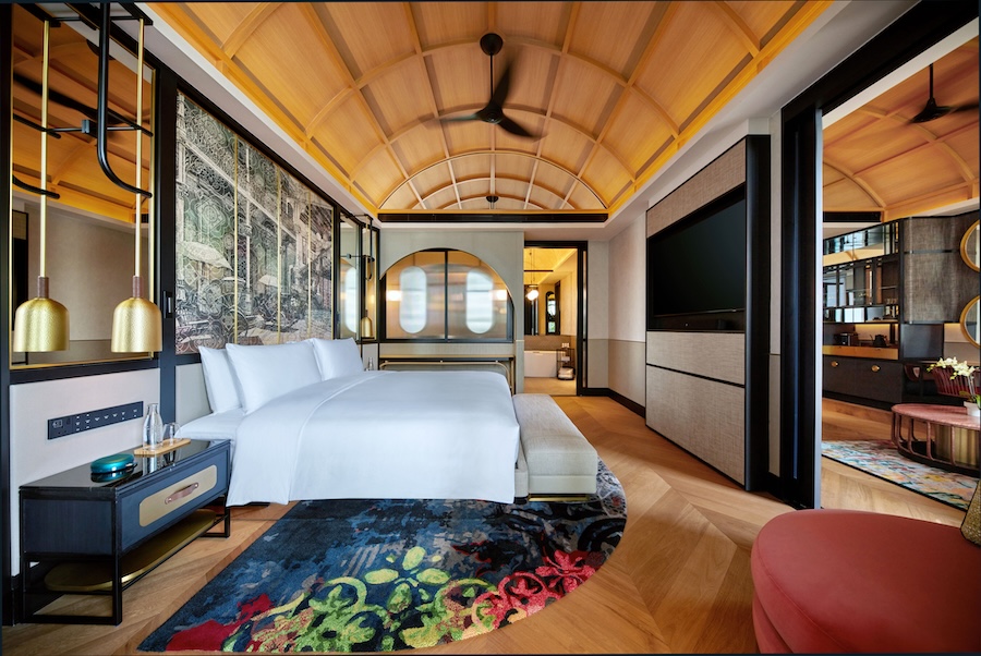 Hotel em Singapura destaca-se pelos grandes jardins verticais tropicais. Na foto, quarto de hotel com tapete colorido, quadro, teto abobadado.