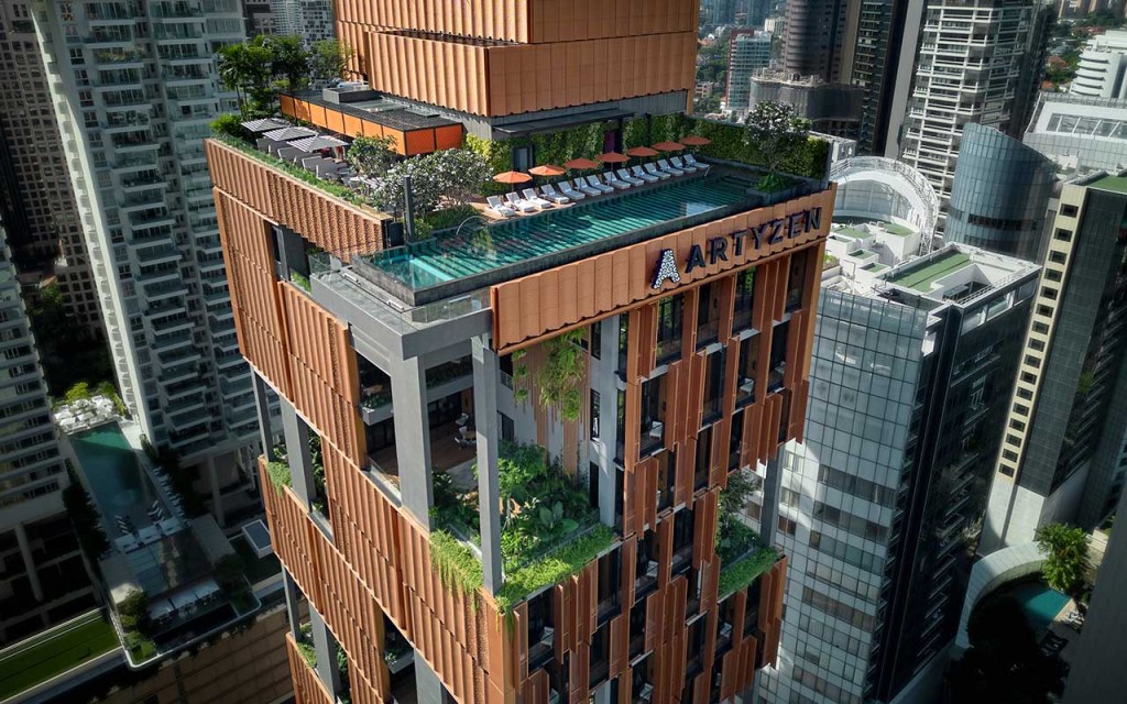 Hotel em Singapura destaca-se pelos grandes jardins verticais tropicais. Na foto, fachada de hotel com piscina e jardins.