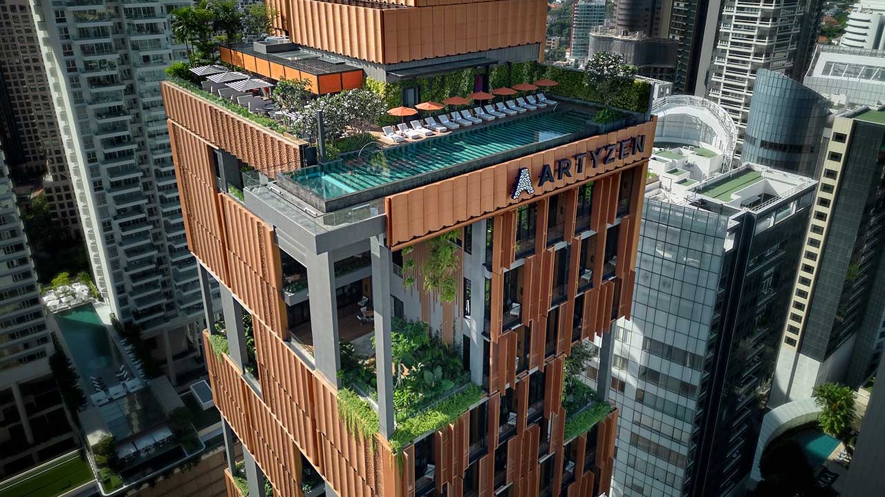 Hotel em Singapura destaca-se pelos grandes jardins verticais tropicais. Na foto, fachada de hotel com piscina e jardins.