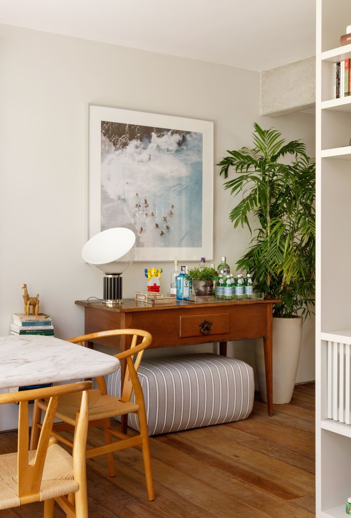 Mezanino é transformado em quarto nesta cobertura de 95 m². Projeto de DCC Arquitetura. Na foto, sala, mesa vintage com bandeja de bar, plantas, pufe, mesa de jantar.