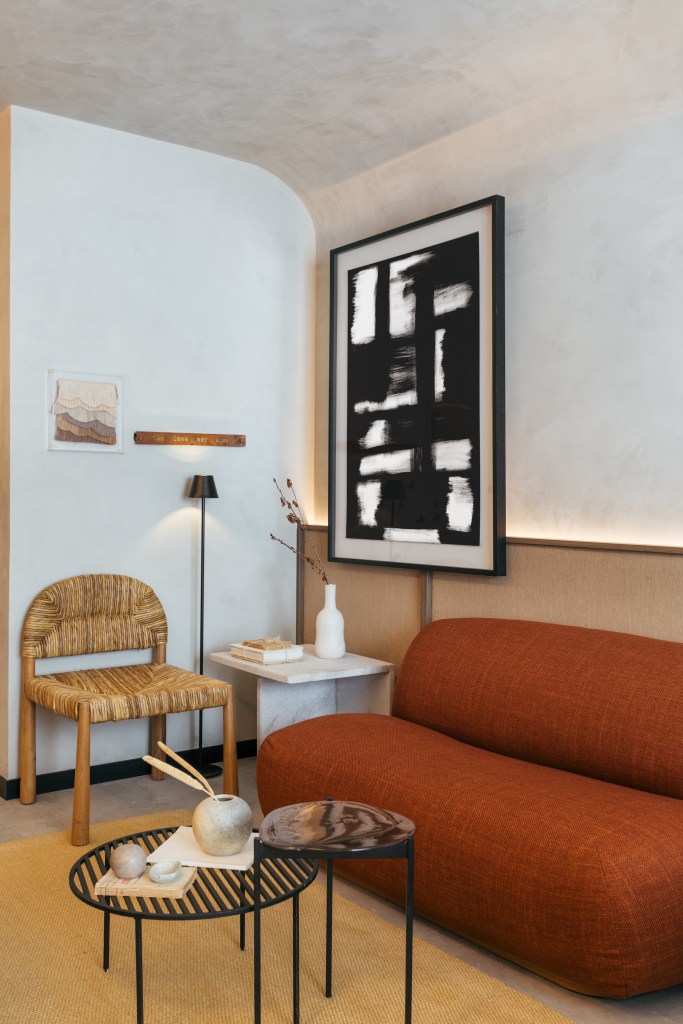 Mini loft de 28 m² ganha décor wabi-sabi com tons terrosos e minerais. Projeto de Studio Leandro Neves. Na foto, sala de estar, sofá terracota, cadeira de palhinha.