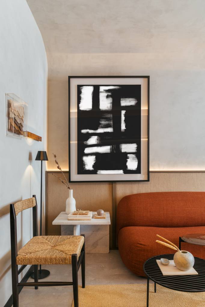 Mini loft de 28 m² ganha décor wabi-sabi com tons terrosos e minerais. Projeto de Studio Leandro Neves. Na foto, sala de estar, sofá terracota, cadeira de palhinha.