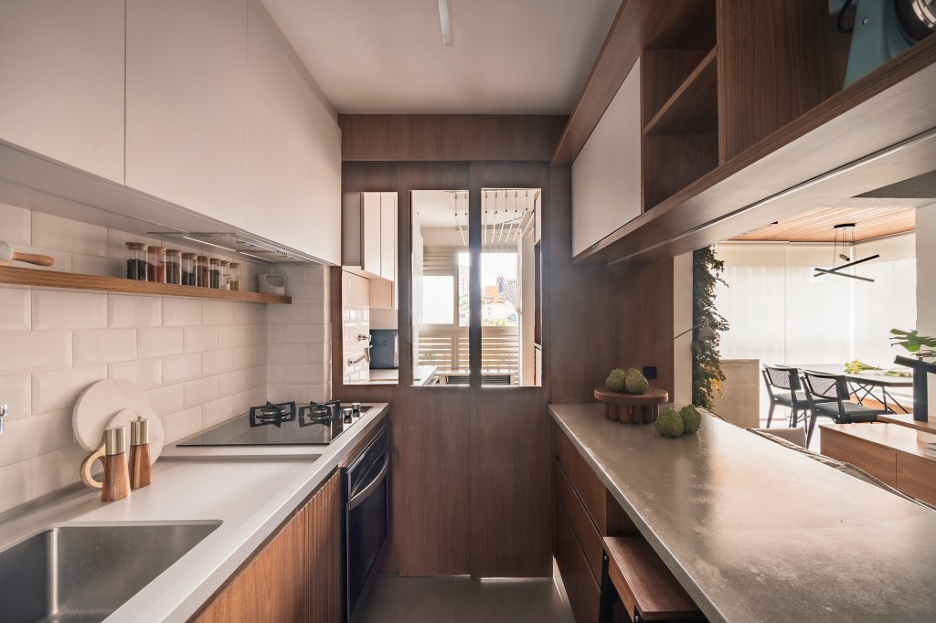 Mix de elementos naturais e industriais marca décor deste apê de 67 m². Projeto de Box 14 Arquitetura. Na foto, cozinha com península e prateleiras suspensas.