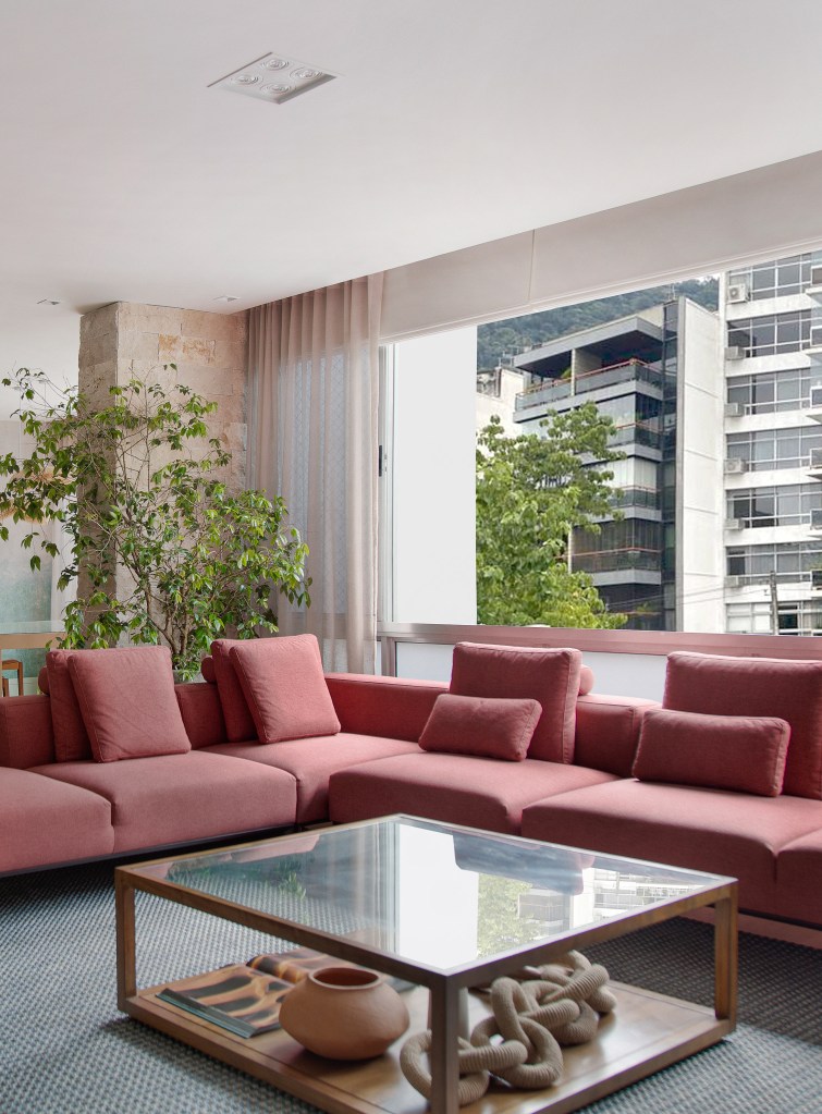 Papel de parede com efeito degradê envelhecido é destaque em área social. Projeto de Manoela Fleck. Na foto, sala de estar, plantas, sofá vermelho terroso.