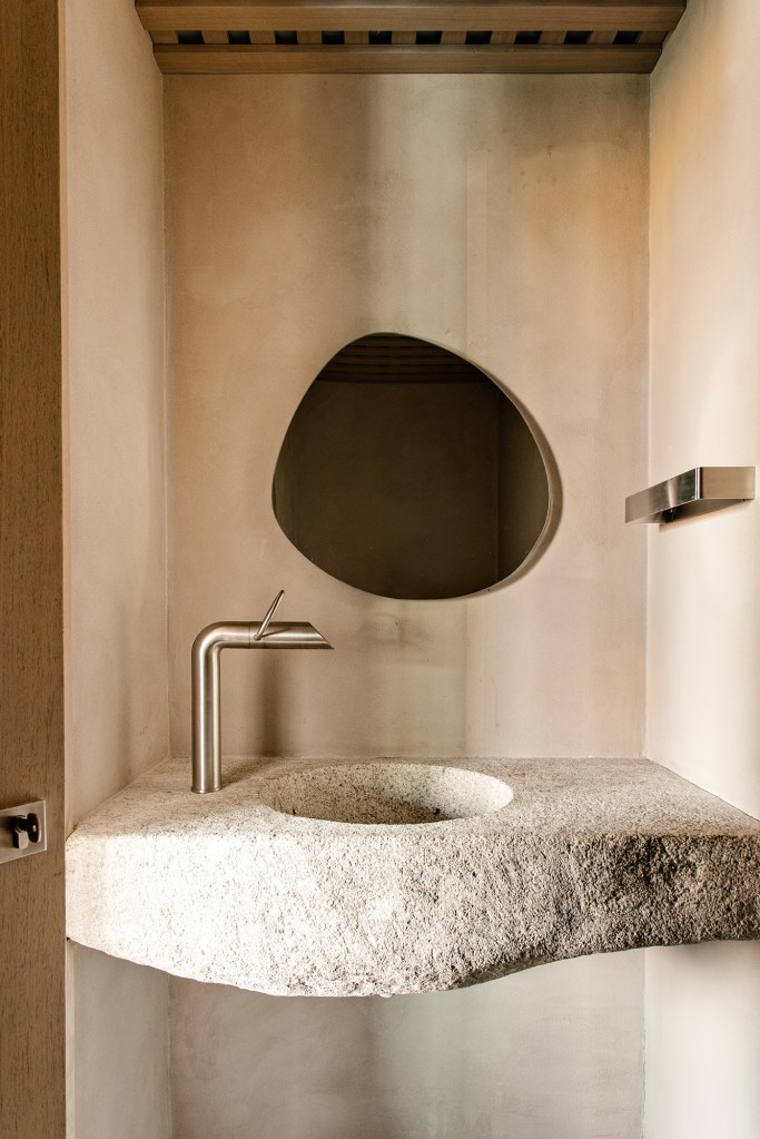 Passarelas com estantes abrigam as coleções do morador deste apê de 420 m². Projeto de Natália Minas e Gabriela Mestriner. Na foto, banheiro com cuba de pedra esculpida.
