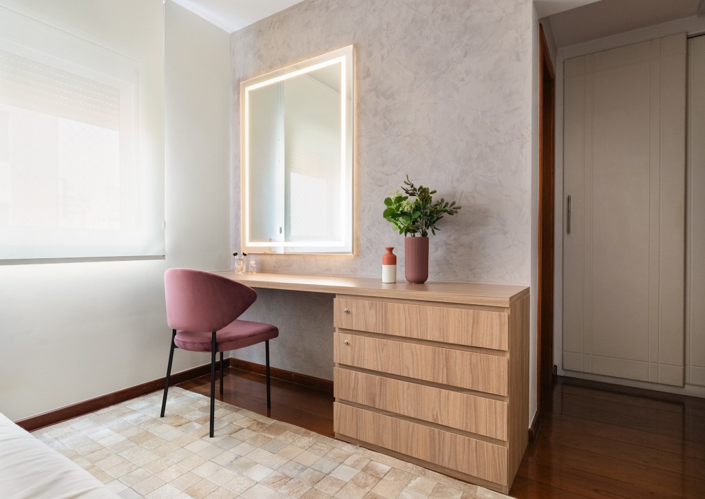Reforma para casal de aposentados nivela piso e integra ambientes de apê. Projeto de Duno Arquitetura. Na foto, quarto, penteadeira, espelho iluminado, cadeira rosa.