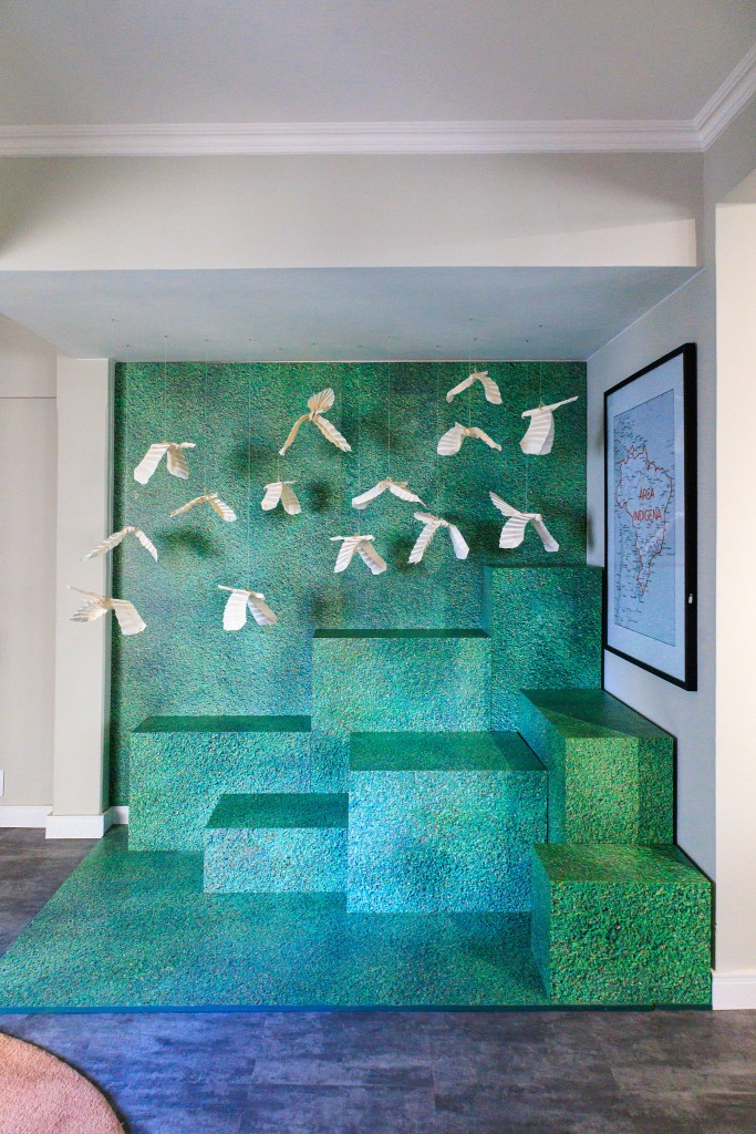 Sala é inspirada na obra de Zé Celso e na exuberância da Amazônia. Projeto de Jordana Fraga. Na foto, instalação com pássaros de papel e MDF verde.